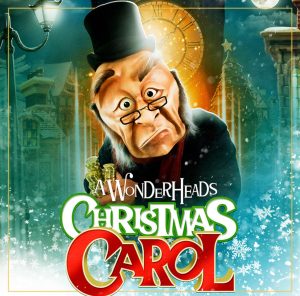 The Wonderheads Christmas carol poster. A green background with a large clock. Ebenezer Scrooge is in the centre represented with a large mask, his face somewhat turned down on one side.