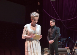 A photo of the original stage play of Onegin. Tatiana stands in the centre of the stage holding a letter. Onegin is behind her. Their expressions are difficult to parse.